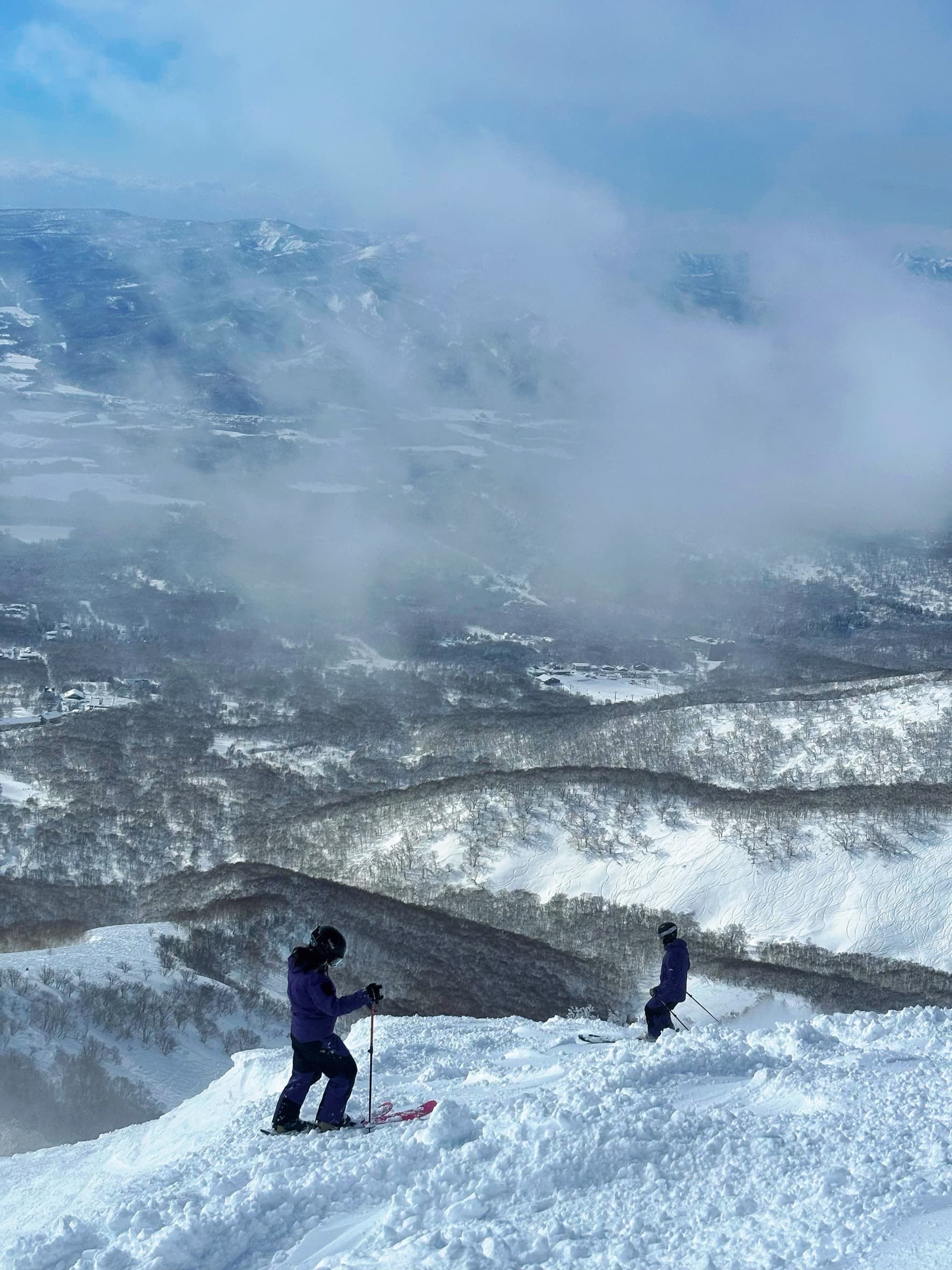 兩位滑雪客站在山頭,俯瞰二世谷山谷與雲海