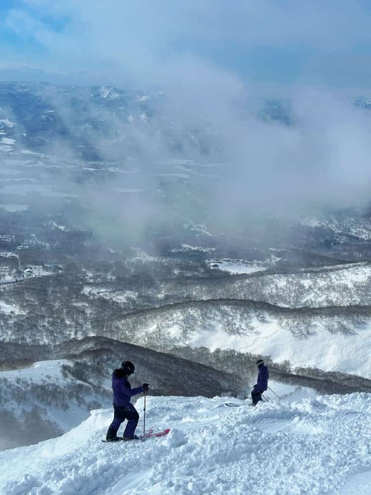 二世谷山頂，兩位滑雪者準備往下滑，背後是雲海與山谷