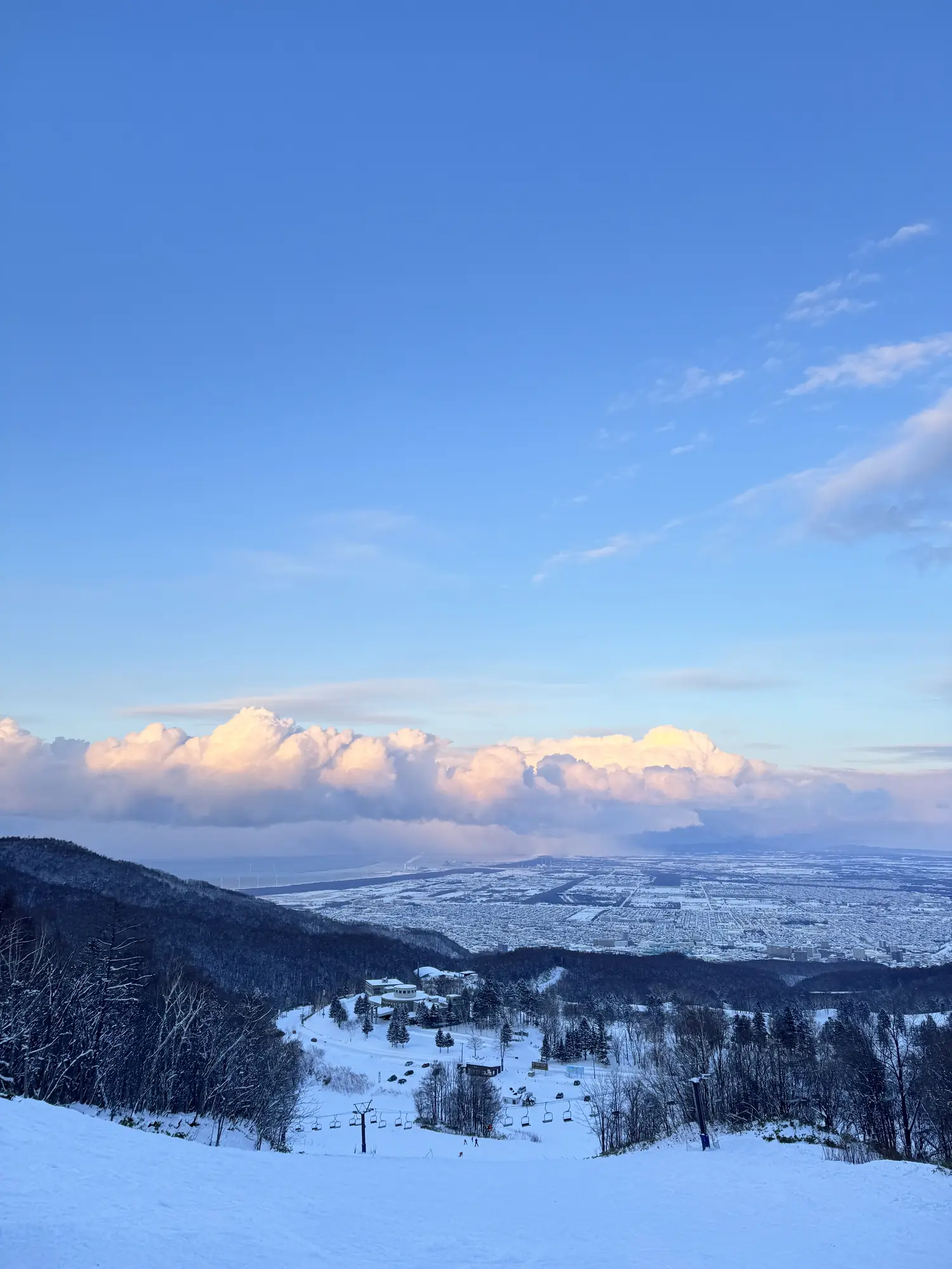 手稻雪道上方的雲層，下方是札幌平原與纜車塔