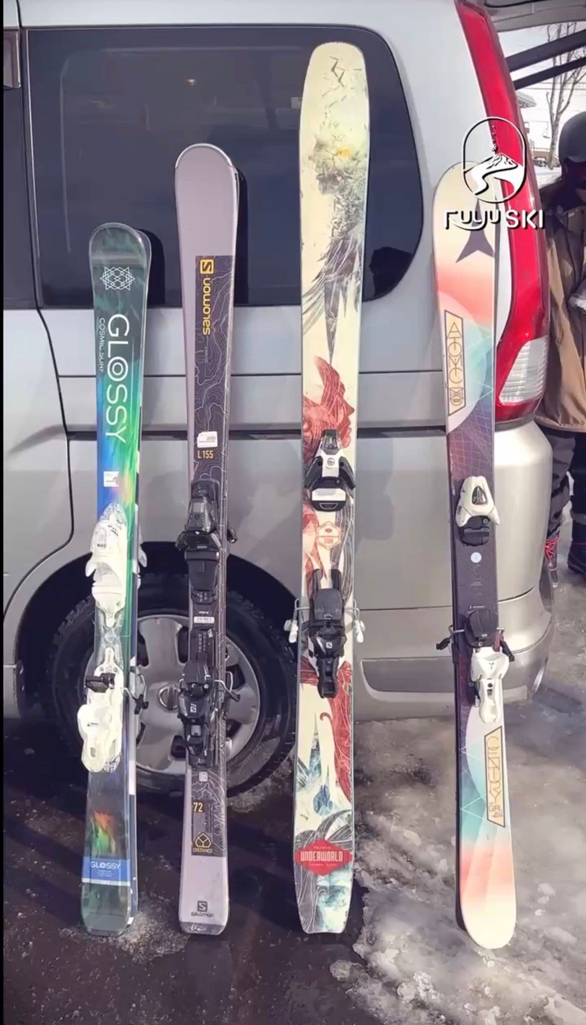 四副雙板靠在接駁車旁的雪地上,板面花色各不相同