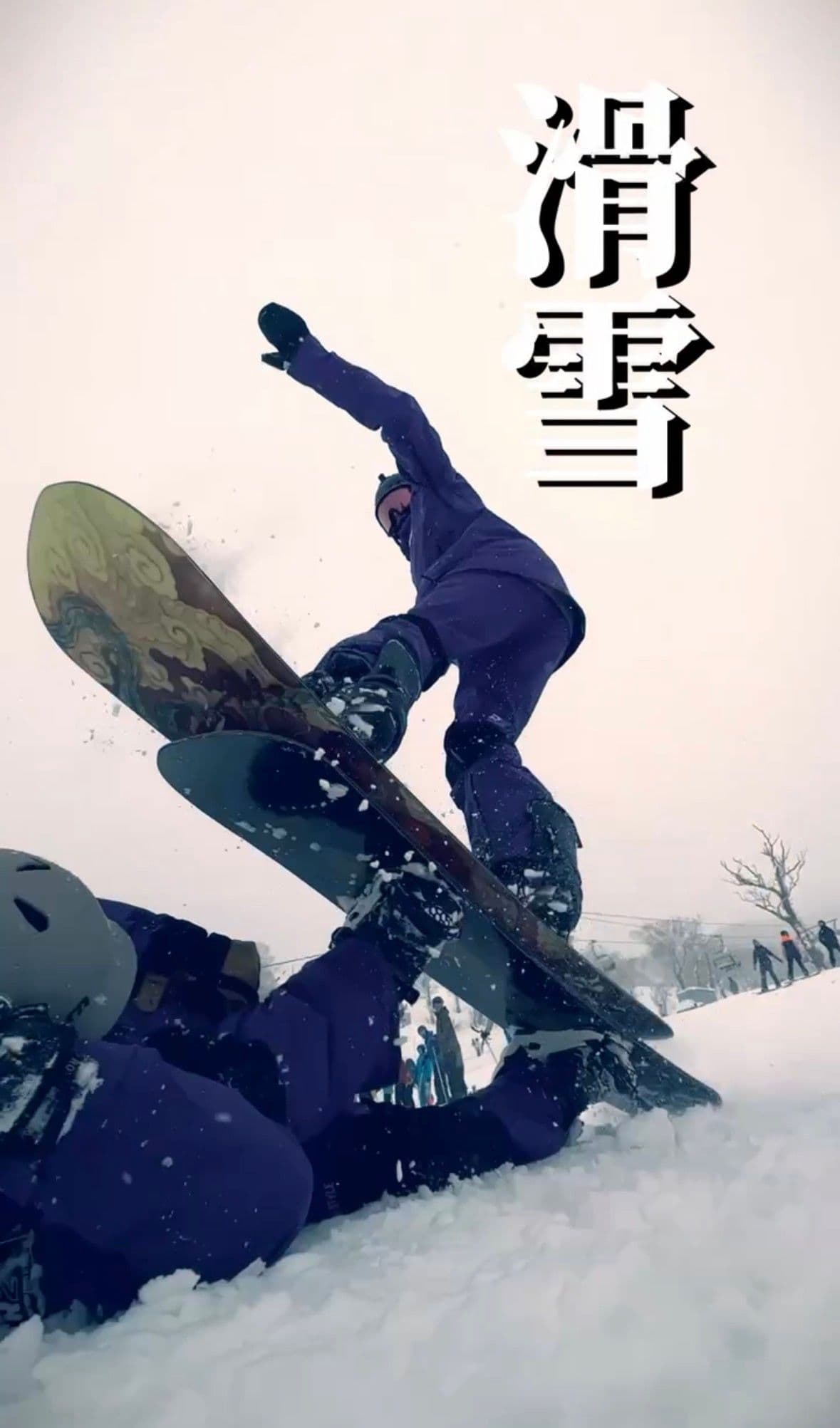 下雪天裡一位單板客在雪地上起跳,板面朝向鏡頭,另一位同伴在前景