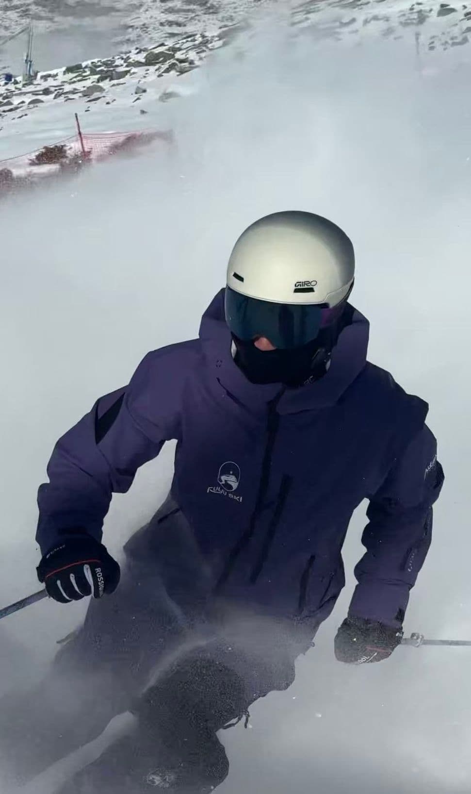 FUYU 教練穿紫色雪衣在粉雪中滑行,雪花在身後捲起